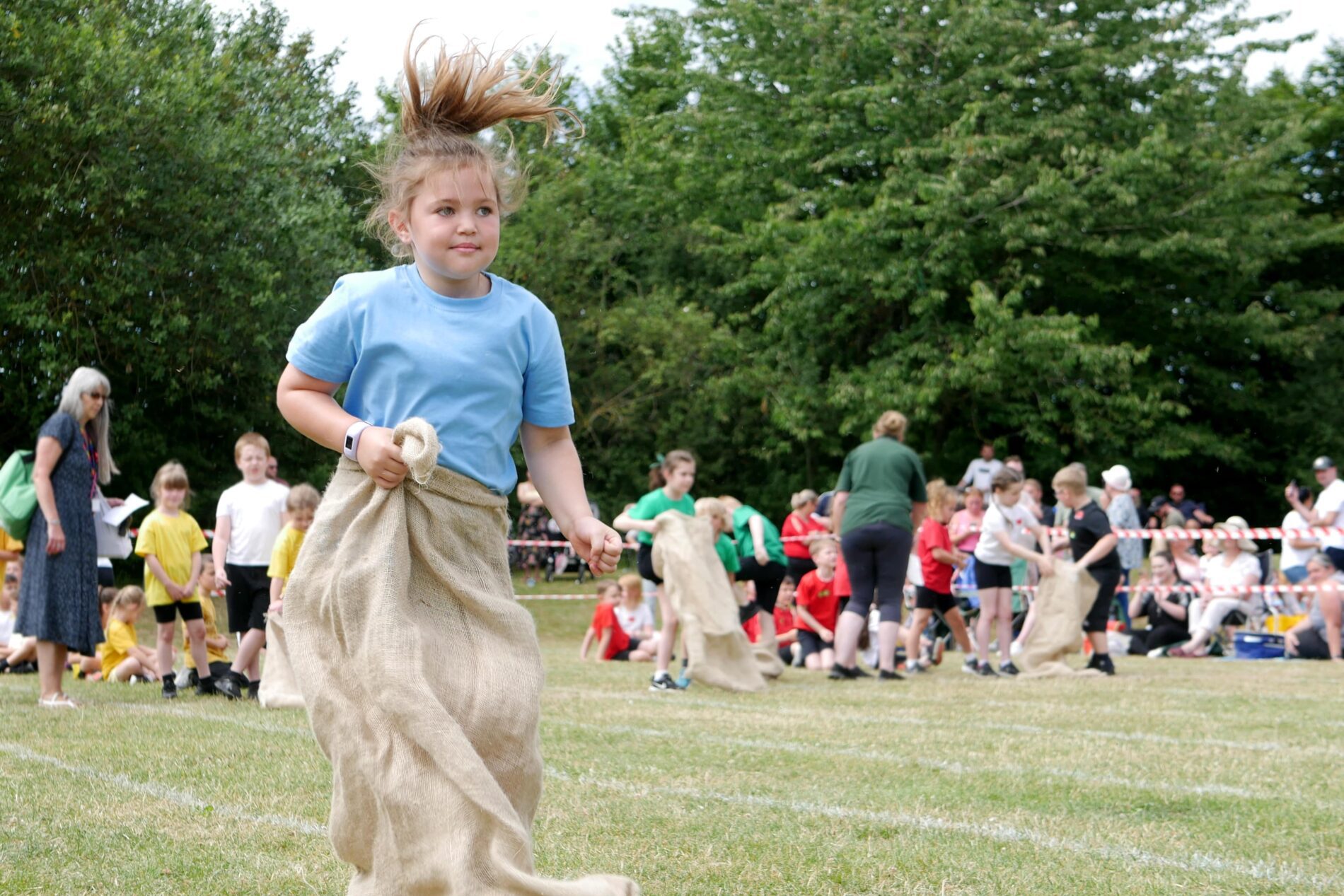 P1130814 pupil jumping in a sack race during sports day as part of physical education